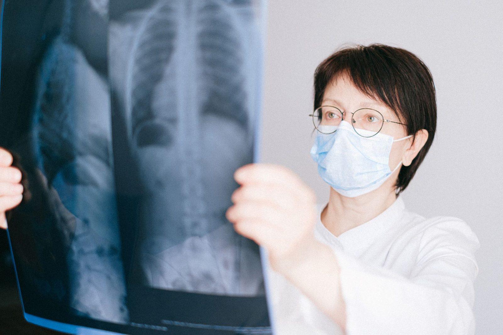 Physician in a face mask holding up a chest X-ray