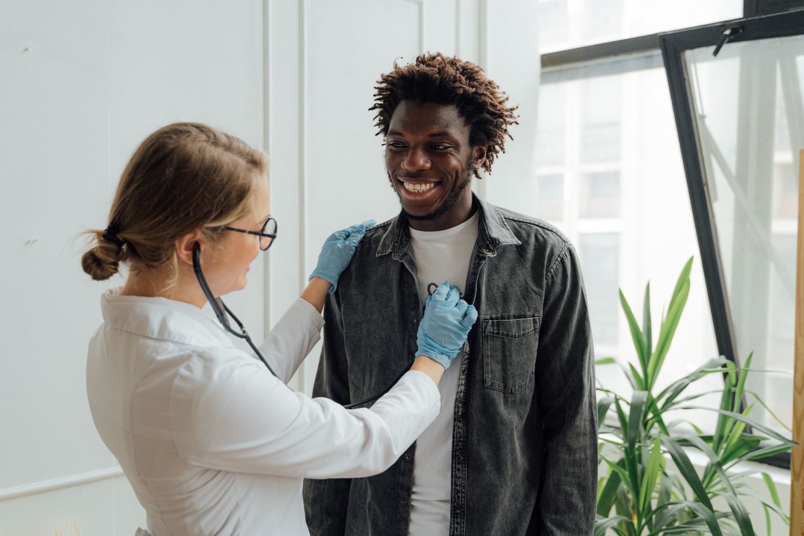 Physician listening to a smiling patient's chest with a stethoscope