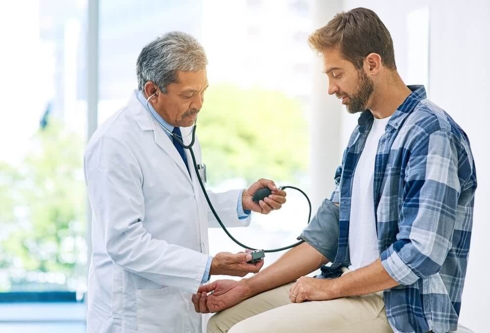 Physician checking a patient's blood pressure with a cuff and stethoscope