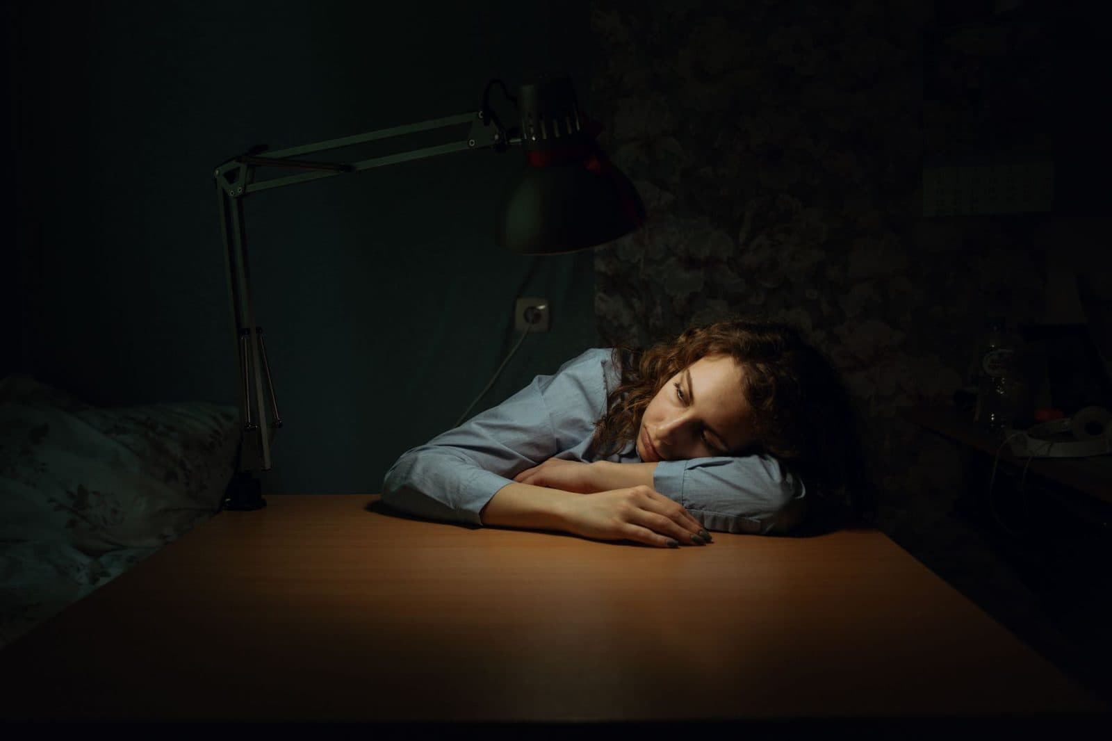 Tired woman resting her head on a desk in a dim room