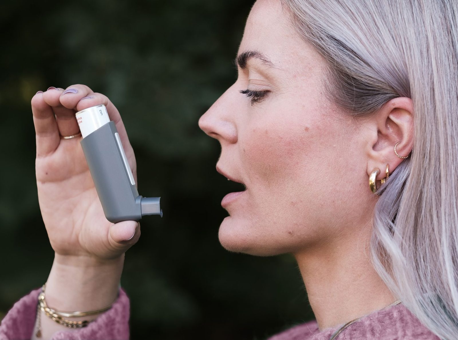 Woman using an asthma inhaler outdoors
