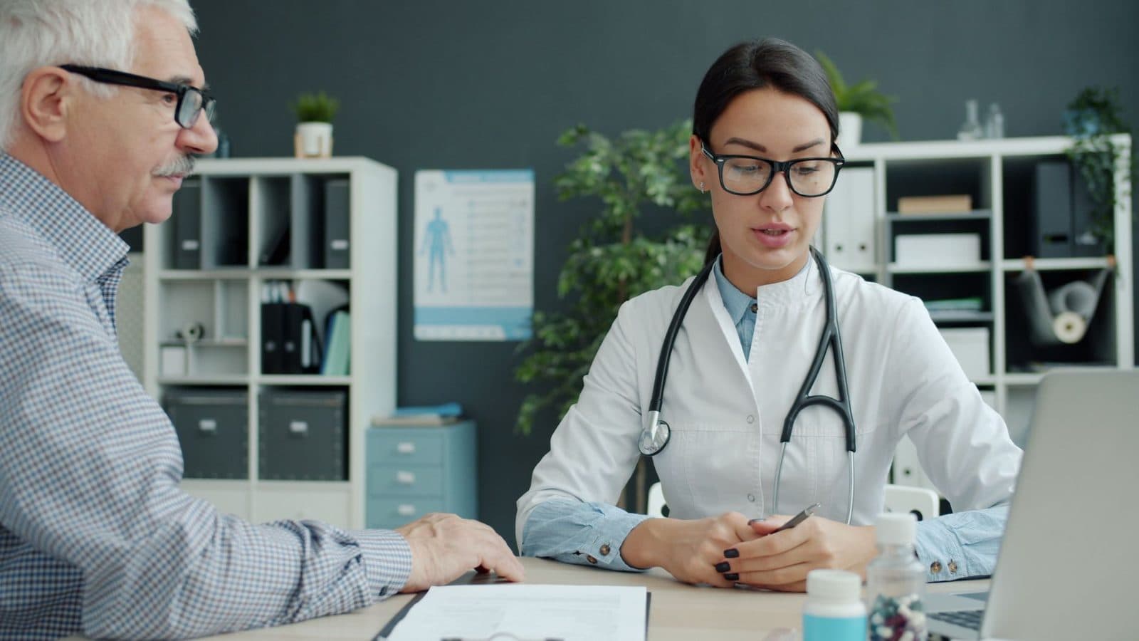 Physician talking with an older male patient across a desk in a medical office