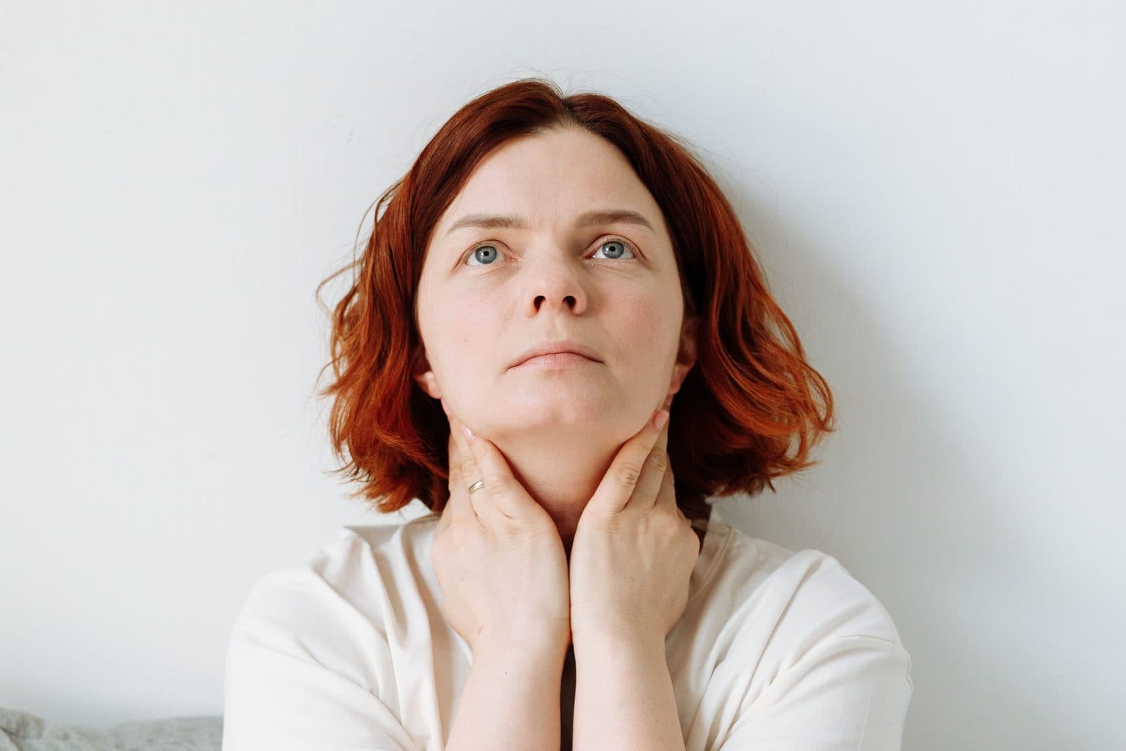 Woman gently touching the front of her neck with both hands