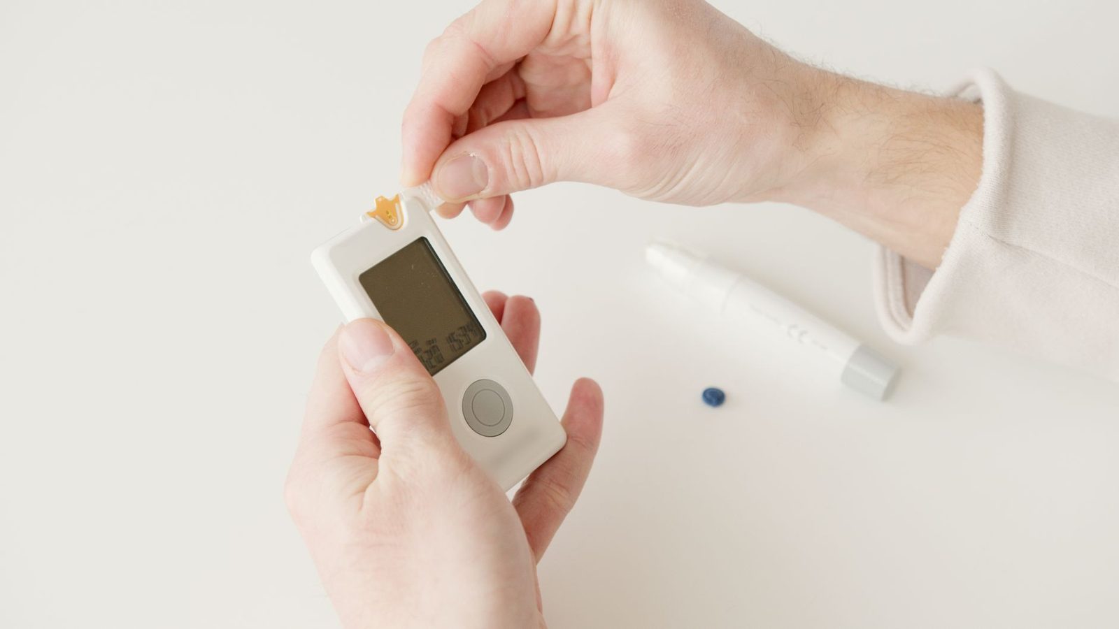 Hands checking a blood glucose reading on a glucometer